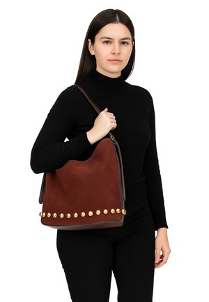 Borsa a spalla in suede marrone con un design morbido, borchie dorate lungo il bordo inferiore e una tracolla in pelle scura a contrasto.