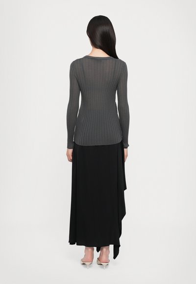 Dark gray ribbed long-sleeve top paired with a flowing black skirt. The outfit features a fitted design with a lightweight texture.