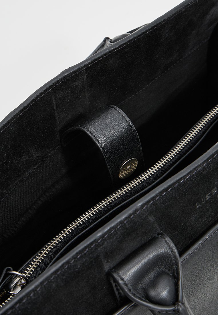 Schwarze Ledertasche mit Wildleder-Innenfutter, ausgestattet mit einem Reißverschlussfach, glatter Textur und einem magnetischen Verschlussdetail.