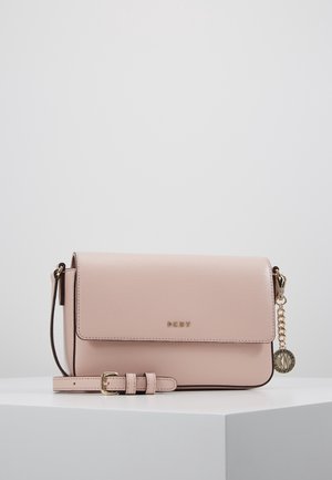 Lichtroze leren DKNY crossbodytas met klep, gouden gesp aan de riem en een ronde gouden DKNY hanger aan de zijketting.