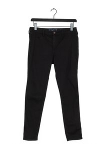 Svarta slim-fit jeans hängande på en svart klädhängare med klipp mot en vit bakgrund.