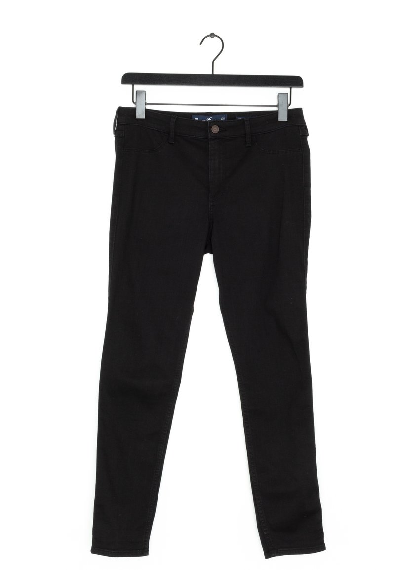 Svarta slim-fit jeans hängande på en svart klädhängare med klipp mot en vit bakgrund.