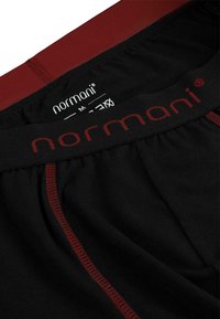 Black boxer briefs with a red waistband, featuring contrasting stitching and a label inside with the brand name "normani."