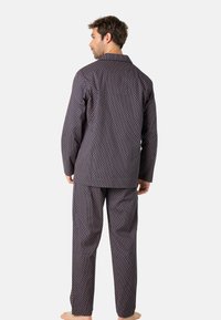 Ensemble de pyjama à motif marine comprenant une chemise à col et un pantalon assorti. Le tissu présente un design géométrique avec des couleurs contrastées et est léger.
