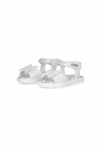 White sandals with a shiny finish, butterfly detail on the front, and patterned insole. Adjustable strap and rugged sole for traction.