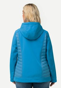 Blå softshell-jacka med huva, med en quiltad textur på sidorna. Slätt material, skräddarsydd passform med sömmar.