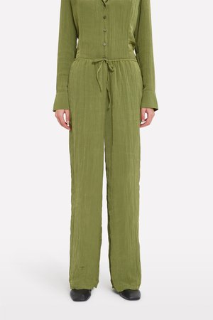 Olive green jumpsuit with a textured finish, long sleeves, buttoned front, adjustable waist tie, and wide-leg design.