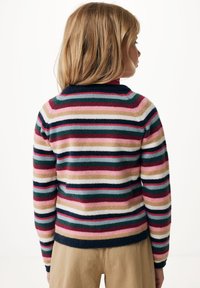 Pruhovaný svetr s horizontálními pruhy v růžové, námořnické, zelené a krémové barvě. Tkanina vypadá měkce s žebrovaným výstřihem a manžetami.