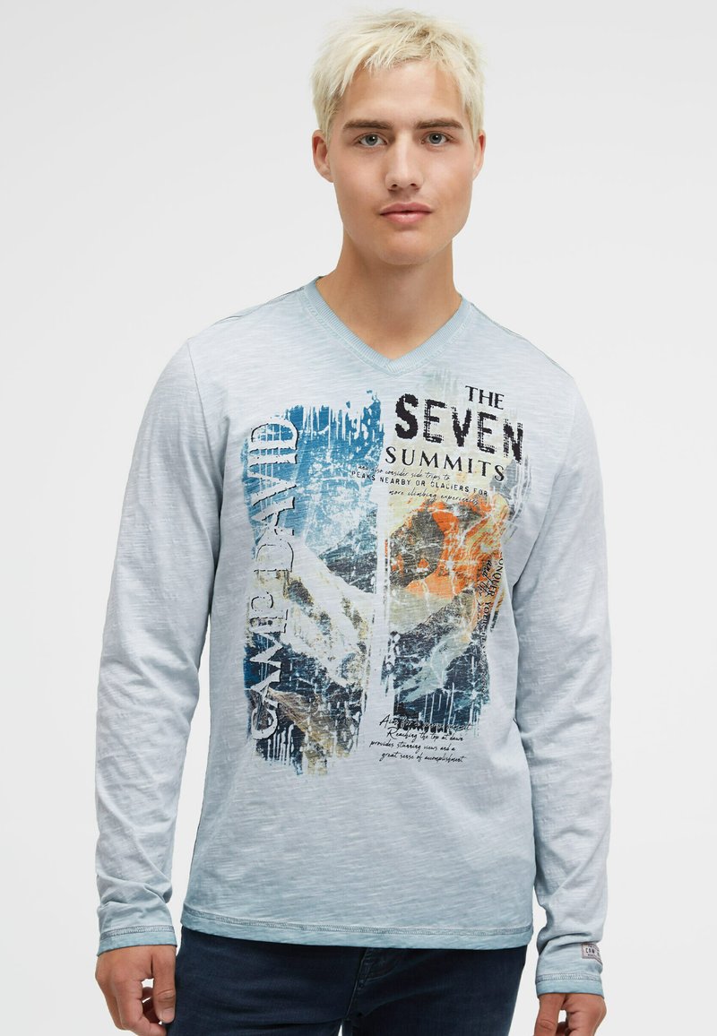 Langarm-T-Shirt in Hellblau mit V-Ausschnitt, versehen mit einem grafischen Druck von Bergen und mehrfarbigem Text. Weicher Stoff, lässige Passform.