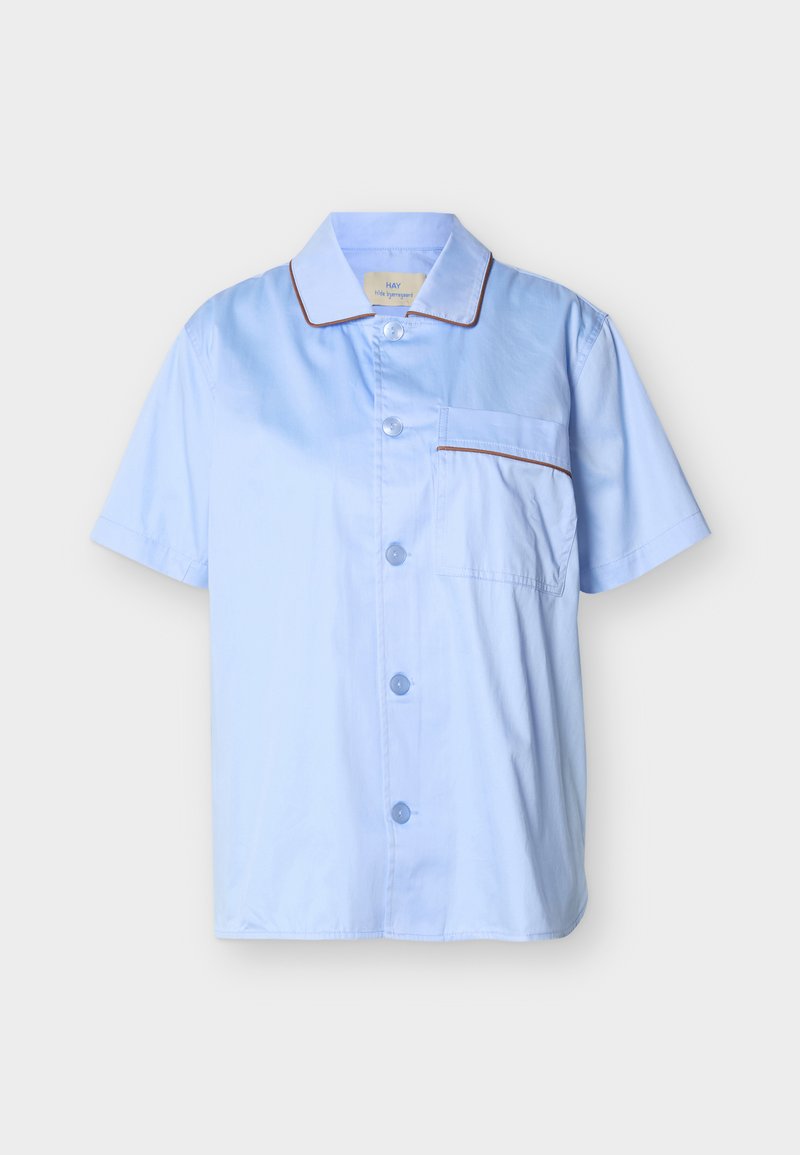 Ανοιχτό μπλε κοντομάνικο πουκάμισο με κουμπιά, με καφέ περιθώρια στον γιακά και στην τσέπη στο στήθος, εμφανίζεται σε απλό φόντο.