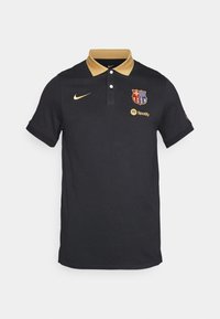 Černé polo tričko vyrobené z bavlny se zlatým límcem a akcenty. Obsahuje logo Nike a znak FC Barcelona. Krátké rukávy, normální střih.