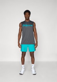 T-shirt sans manches gris avec "Miami Dolphins Football" en turquoise, associé à un short turquoise avec des accents noirs et un logo noir.