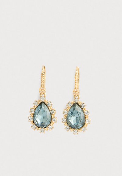 Orecchini a goccia in oro con pietre preziose blu a forma di goccia circondate da piccoli cristalli trasparenti su sfondo bianco.