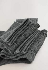 Calcetines de lana gris con un patrón texturizado, doblados de manera ordenada. El diseño presenta puños acanalados y un tejido suave y texturizado.
