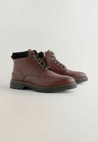 Braune Leder-Ankle-Boots mit schwarzem Wildlederkragen, Schnürverschluss vorne und seitlichem Reißverschluss, ausgestattet mit einer robusten Gummisohle mit rutschfestem Muster.