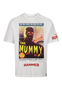 T-shirt en coton blanc avec un design de poster de film vintage pour "La Momie", comportant un texte en jaune et rouge vif et une illustration d'une figure de momie.