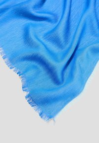 Écharpe bleue avec une texture douce et lisse, présentant des bords effilochés et un design dégradé, passant du bleu clair au bleu foncé.