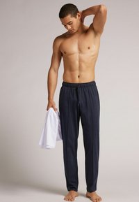 Marineblauwe lichtgewicht joggingbroek met een elastische tailleband, trekkoordsluiting en een zachte textuur, gecombineerd met een plain wit shirt.