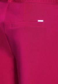 Fuchsia jogger broek met een soepel textuur, elastische tailleband en een enkele achterzak met een subtiele logo-accent.