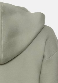 Jasnozielona bluza z kapturem, charakteryzująca się teksturowanym materiałem, okrągłym kapturem oraz widocznymi detalami szwów, podkreślającymi jej swobodny styl.