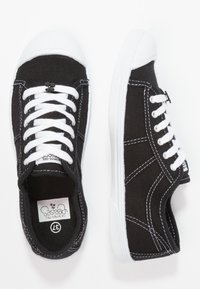 Sneaker nere in tela con suole e punte bianche in gomma. Presentano lacci bianchi e cuciture a contrasto. Etichetta del marchio visibile all'interno.