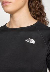Μαύρη αθλητική μπλούζα με υφή, στρογγυλή λαιμόκοψη και μικρό λευκό λογότυπο "The North Face" στην αριστερή περιοχή του στήθους.