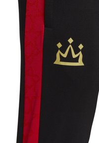 Tela negra con una franja roja vertical que presenta patrones de estrellas y un símbolo de corona dorada en la zona negra.