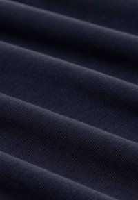 Marineblauer Stoff mit glatter Textur und subtiler diagonaler Rippung, in sich überlappenden Falten angeordnet. Der reiche, dunkle Farbton verstärkt die Tiefe.