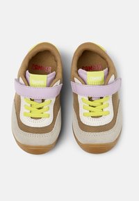 Sneaker in tela e suede marrone con accenti bianchi e lavanda, dotati di un sistema di lacci giallo e una fascia in Velcro; suola in gomma testurizzata.