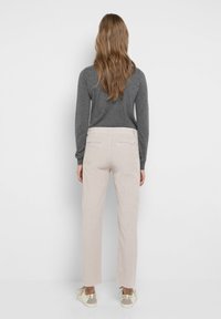Ljust beige manchesterbyxor med raka ben, fransad fåll och bakfickor, tillsammans med en mörkgrå långärmad tröja och låga sneakers.