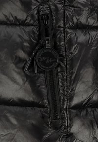 Schwarze Daunenjacke mit glänzendem, gesteppte Außenmaterial, einem zentralen Reißverschluss mit Knebelverschluss und einem runden Markenschild.