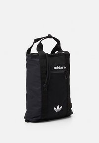 Svart Adidas tote-väska med dubbla handtag, ficka med dragkedja fram, dragsko-stängning och vita Trefoil-logotyper på frampanelen.