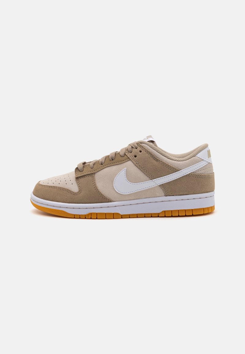 Nike Dunk -kengät, joissa on tan- ja beige-väriä nahkaa ja pörröistä kangasta, valkoisia yksityiskohtia, rei'itetty kärki ja kuminen pohja.
