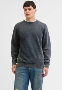 Donkergrijze sweatshirt van zachte stof, met een ronde hals en geribde manchetten. G gedragen met versleten denim jeans, wat een casual stijl benadrukt.