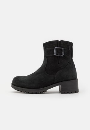 Bottines en daim noir avec un bout rond, un talon moyen et un accent de boucle latérale. Elles sont dotées d'une semelle texturée pour l'adhérence et la stabilité.