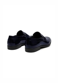 Zapatos de charol azul marino con un acabado suave, tacón bajo y una banda elástica para un ajuste seguro, mostrados desde la parte trasera.