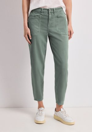 Pantalon vert taille haute coupe droite avec poches plaquées à l'avant, porté avec des baskets blanches et un top léger rentré.