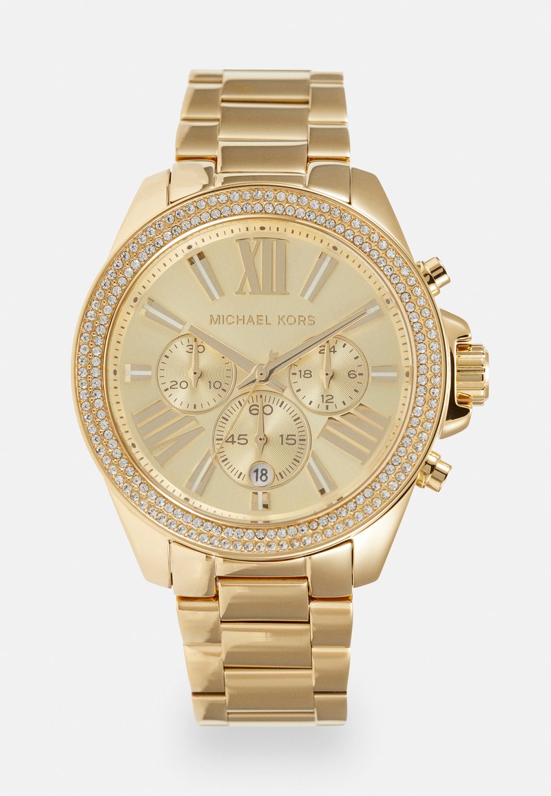 Montre chronographe dorée avec un cadran texturé, le XII en chiffres romains, trois sous-cadrans et une lunette ornée de strass. Bracelet en métal.