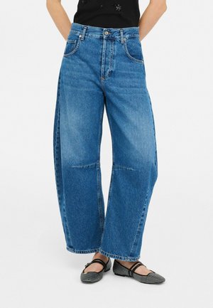 Jeans in denim blu a gamba larga con vita alta, caratterizzati da zone sbiadite, tasche frontali e cuciture a contrasto.