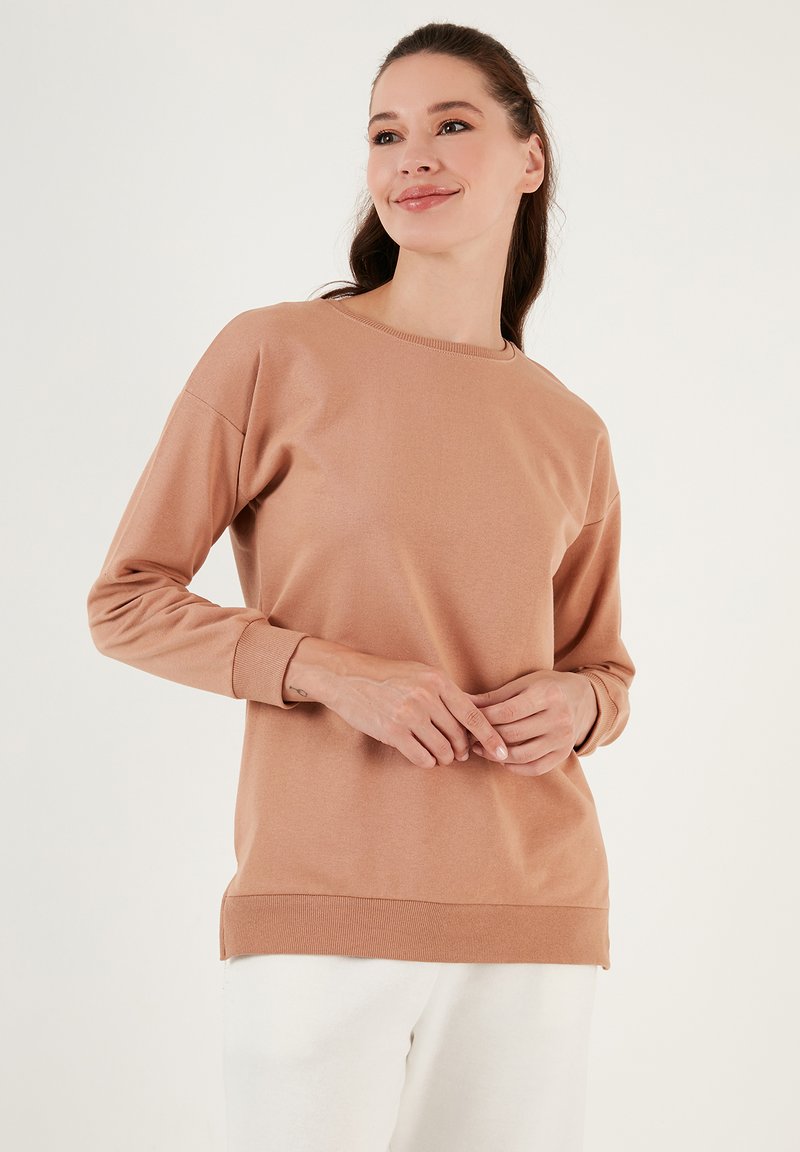Felpa a maniche lunghe color marrone chiaro in morbido tessuto con scollatura a girocollo, polsini a costine e vestibilità rilassata, caratterizzata da un design pulito.