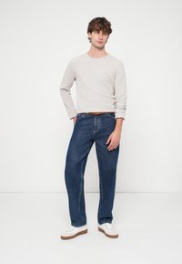 Ανοιχτό γκρι πουκάμισο με μακριά μανίκια, μπλε τζιν παντελόνι φαρδιάς γραμμής, καφέ ζώνη και λευκά αθλητικά παπούτσια. Απαλό ύφασμα με ριμπ υφή και λεπτομέρεια με λογότυπο στο πουκάμισο.