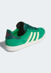 Green suede sneaker with cream stripes, padded collar, and textured white rubber sole. Features logo on the heel and tongue.