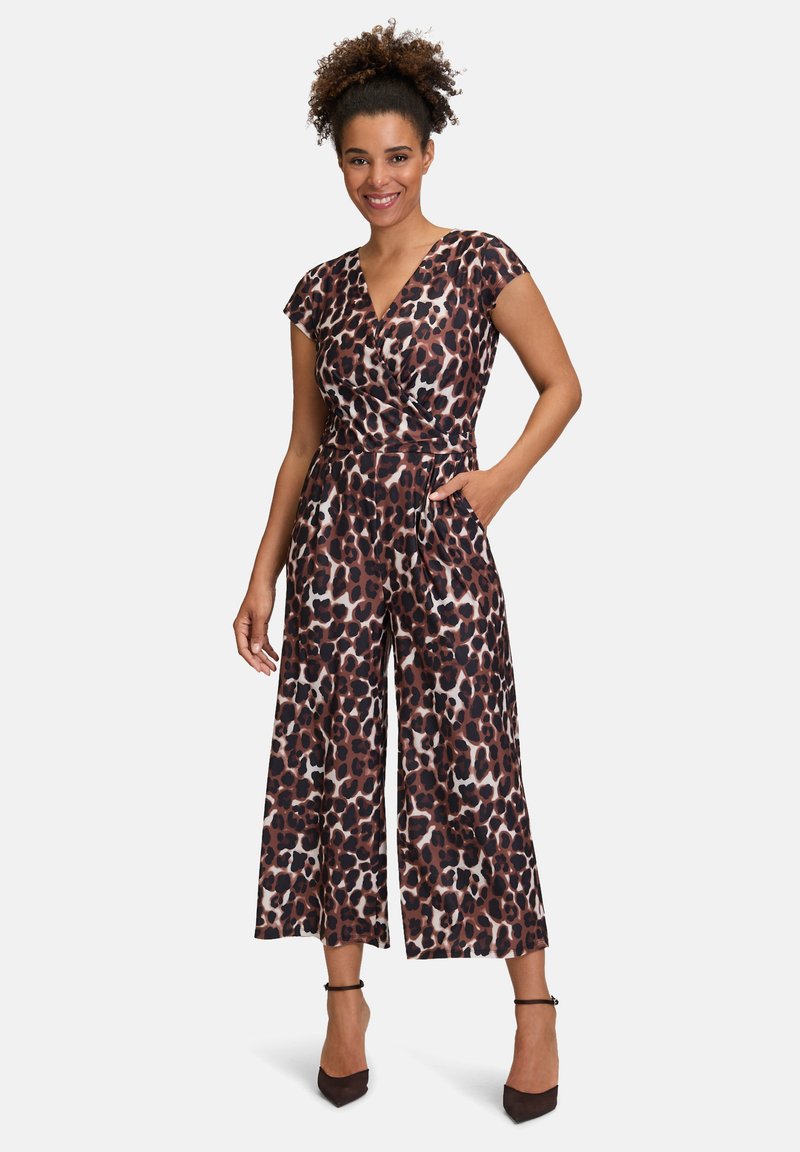Leopardenmuster-Jumpsuit aus weich fließendem Stoff mit Wickeldesign, kurzen Ärmeln, weit geschnittenen, cropped Beinen und Seitentaschen, getragen zu hohen Pumps.