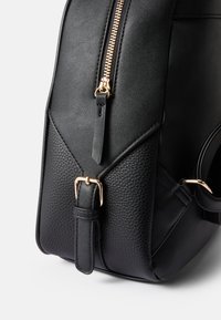 Fekete bőr táska pebbled textúrával és sima kiegészítőkkel. Arany cipzárral és csat hardverrel rendelkezik. Strukturált, szögletes dizájn.