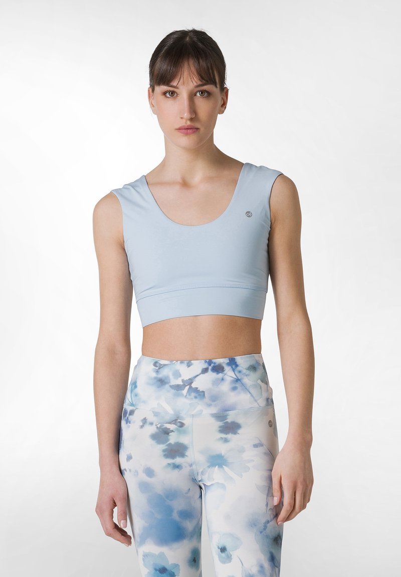 Ljusblåt, kort träningslinne med rund halsringning och ärmlös design; ihop med höga leggings med ett blått blommönster.