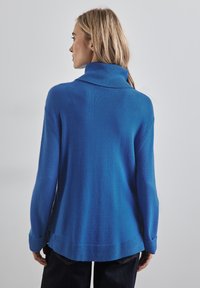Pull en laine mélangée bleu avec un col montant, des poignets et un ourlet côtelés. Présente une coupe décontractée et une texture douce, visible de l'arrière.