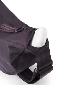 Lila Nylon-Tasche mit strukturierter Oberfläche, ausgestattet mit einem Tragegurt und einem Reißverschlussfach. Auffälliges Detail: ein Plastikclip, der am Tragegurt befestigt ist.