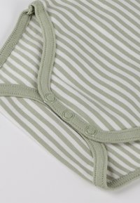 Nahaufnahme eines mintgrünen und weiß gestreiften Babybodys mit drei Druckknöpfen entlang der unteren Kante.