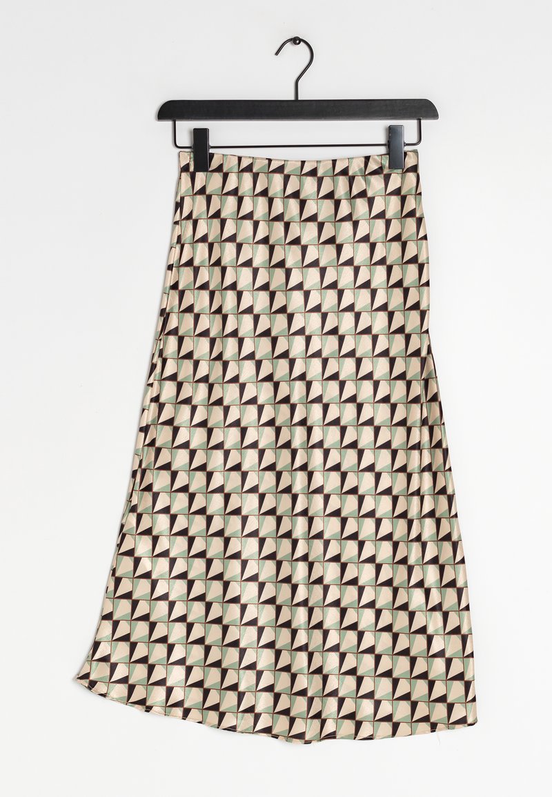 Jupe midi avec motif géométrique de triangles en tons beige, marron et vert, suspendue sur un cintre noir contre un fond blanc.