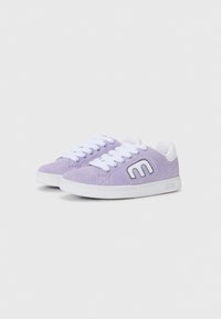 Purple suede sneakers with white accents, featuring a rounded toe, white laces, and a prominent ‘M’ logo on the side. Textured surface.